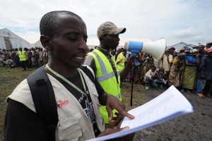 Calling out beneficiary names during an aid distribution in Kibati camp, DRC