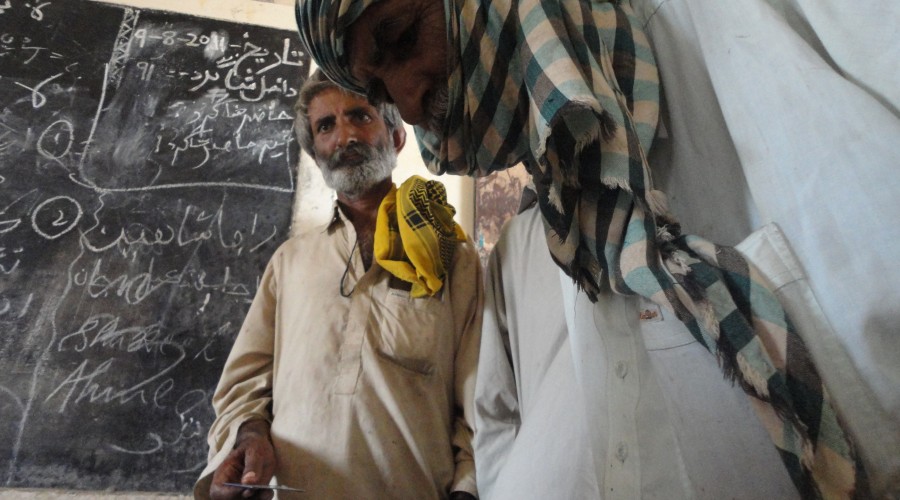 A CBHA beneficiary thumb-stamping a form before receiving payment