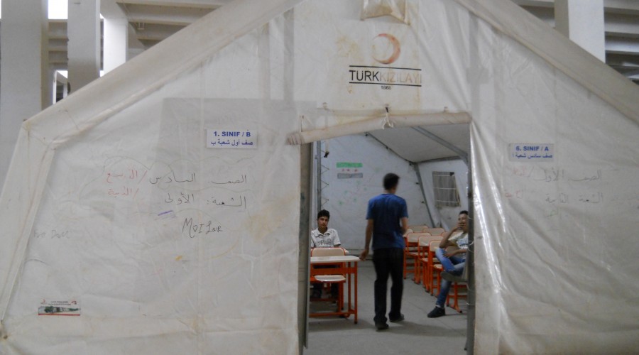 Volunteer Syrian teachers confer in a classroom tent erected in an abandoned warehouse at the Islahiye refugee camp in Turkey