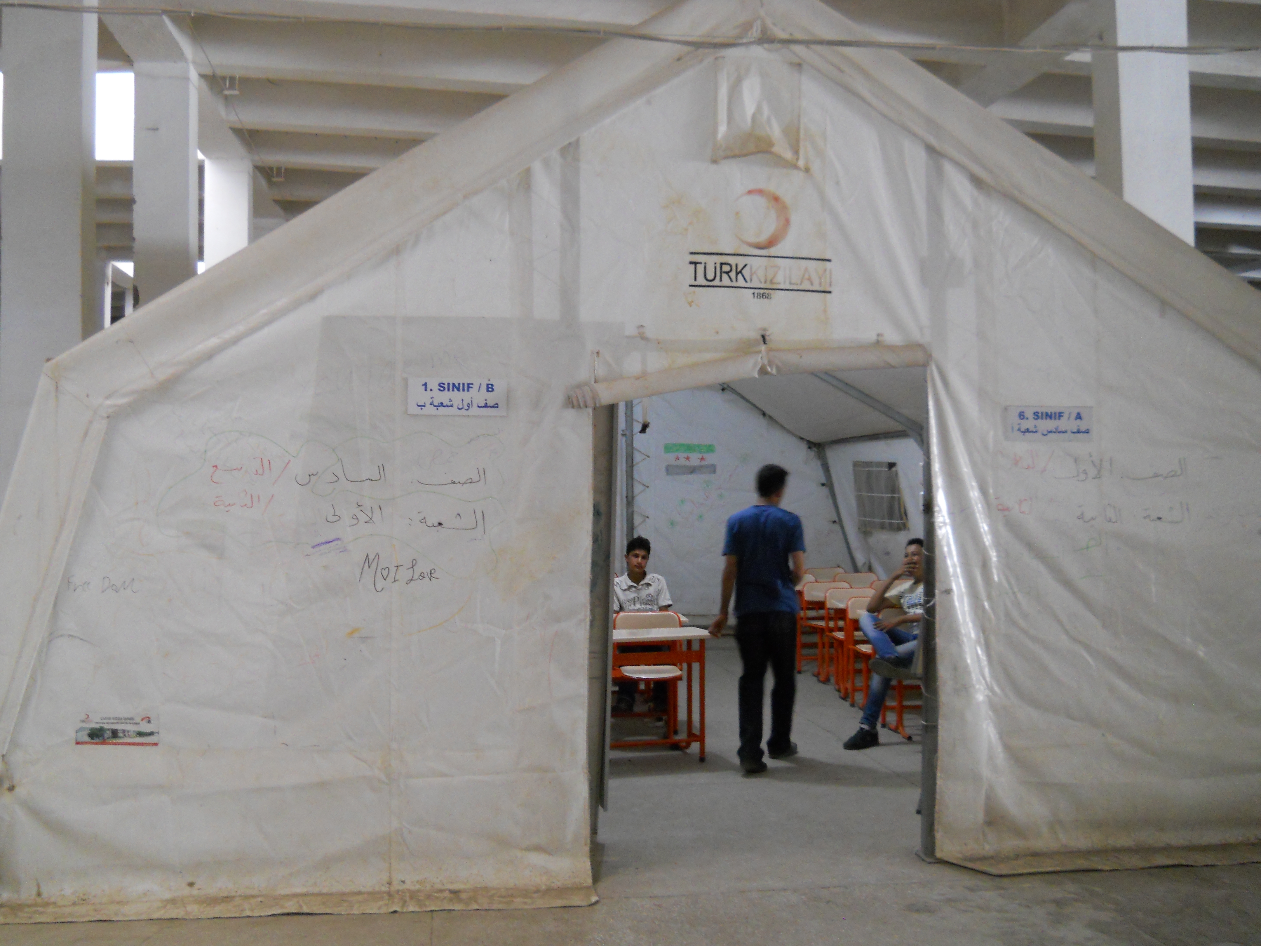Volunteer Syrian teachers confer in a classroom tent erected in an abandoned warehouse at the Islahiye refugee camp in Turkey