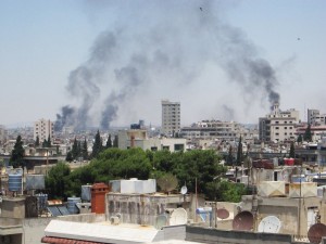 Smoke billows skyward as homes and buildings are shelled in the city of Homs, Syria