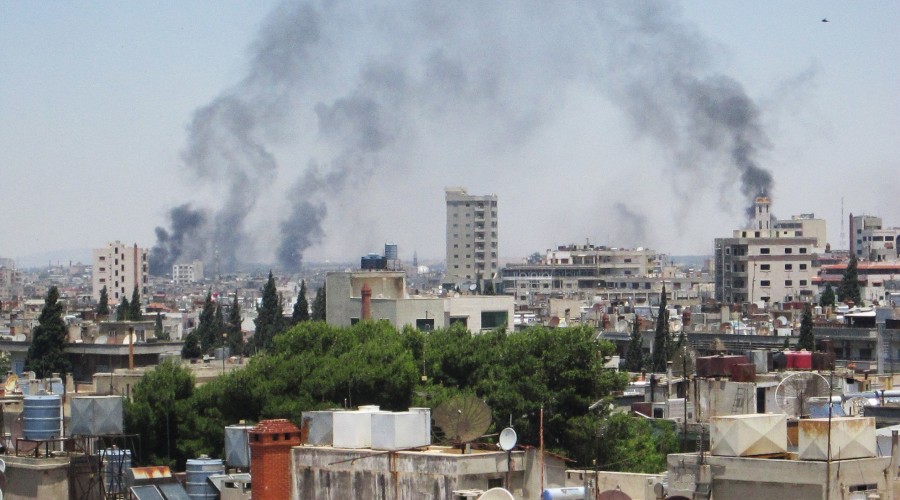 Smoke billows skyward as homes and buildings are shelled in the city of Homs, Syria