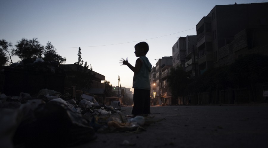 A boy stands next to a pile of debris on a street in Aleppo, capital of the north-western Aleppo Governorate
