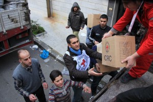 Local people help Syrian Arab Red Crescent volunteers unload food parcels in Homs, Syria