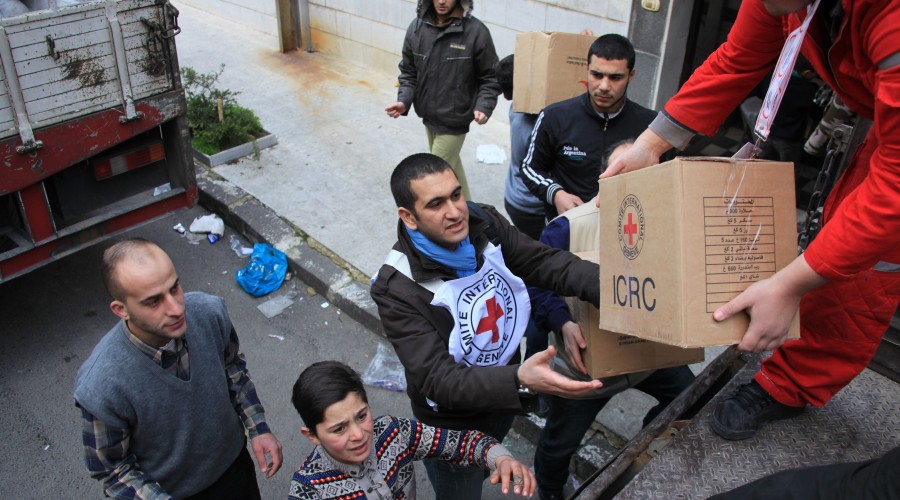 Local people help Syrian Arab Red Crescent volunteers unload food parcels in Homs, Syria