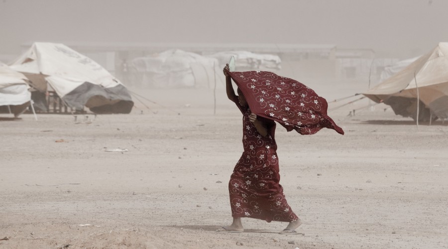 A girl makes her way through windswept Mentao refugee camp near Djibo, Burkina Faso