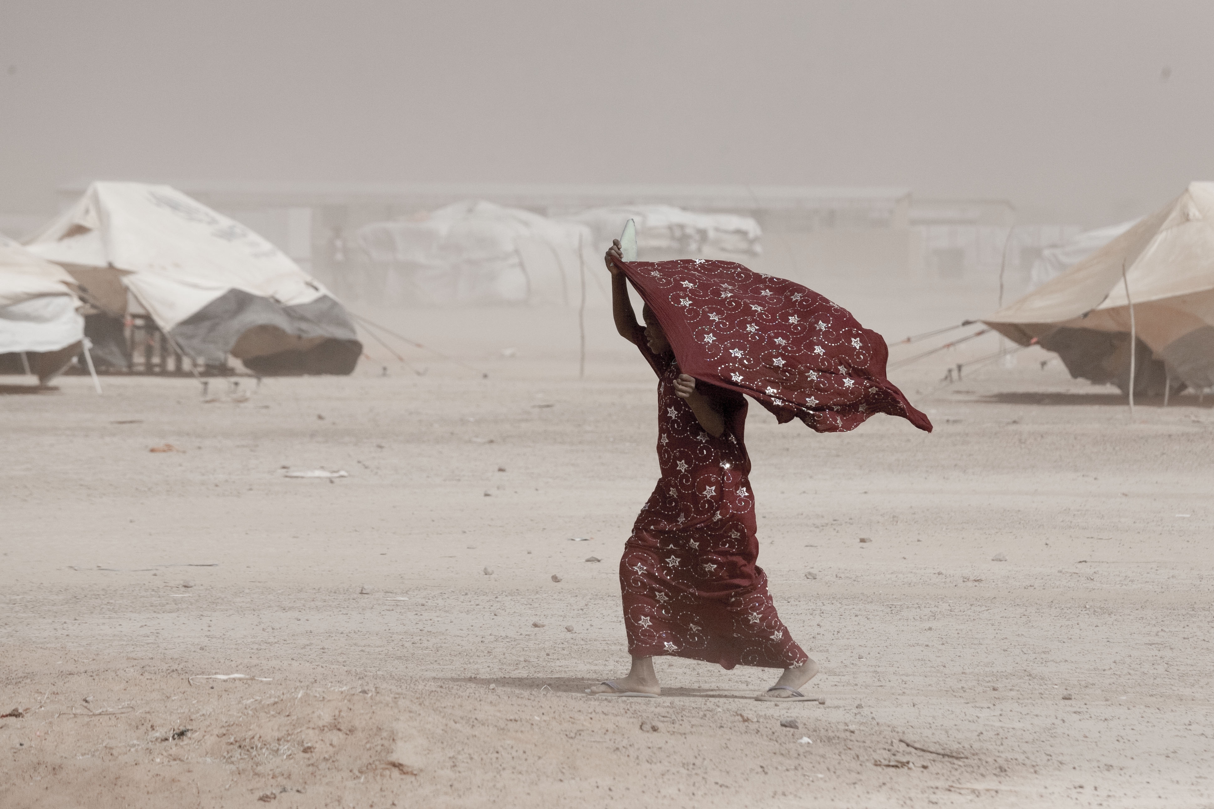 A girl makes her way through windswept Mentao refugee camp near Djibo, Burkina Faso