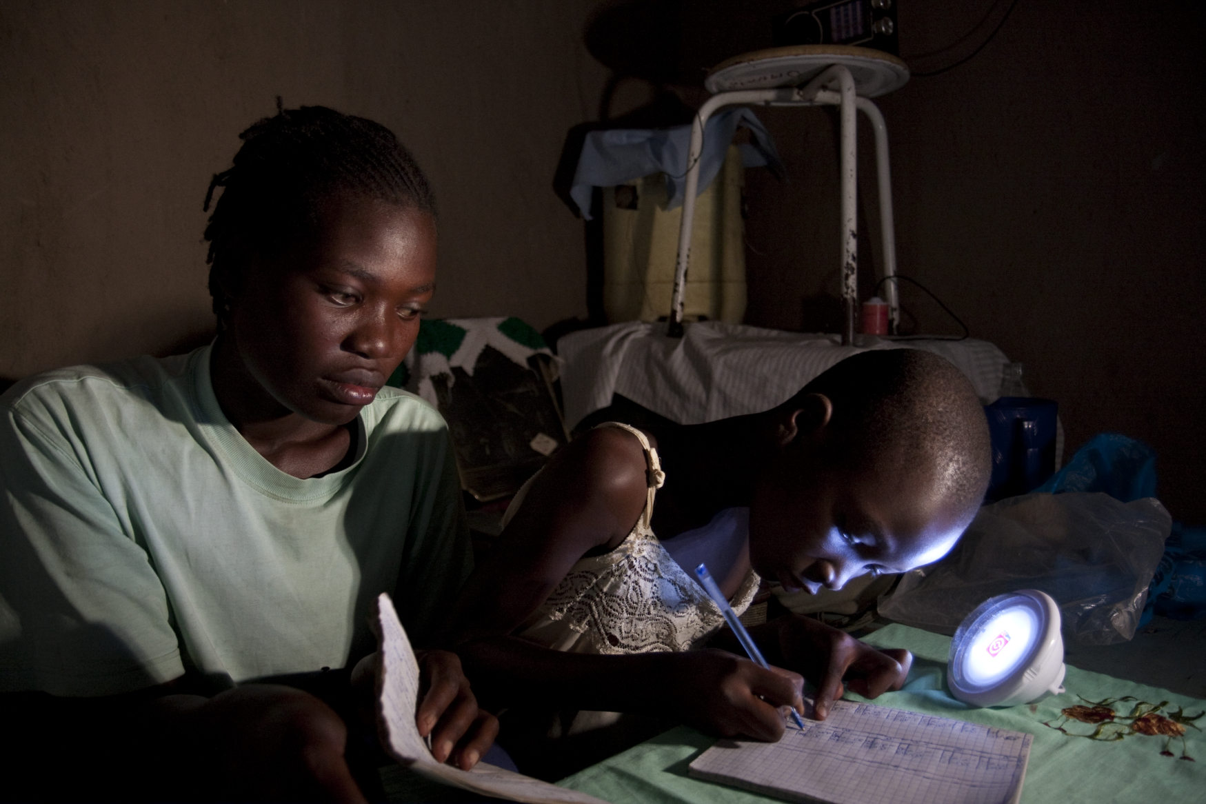 Girl studies at night using solar powered light bought from an entrepreneur trained by Christian Aid partner ADS, Kenya