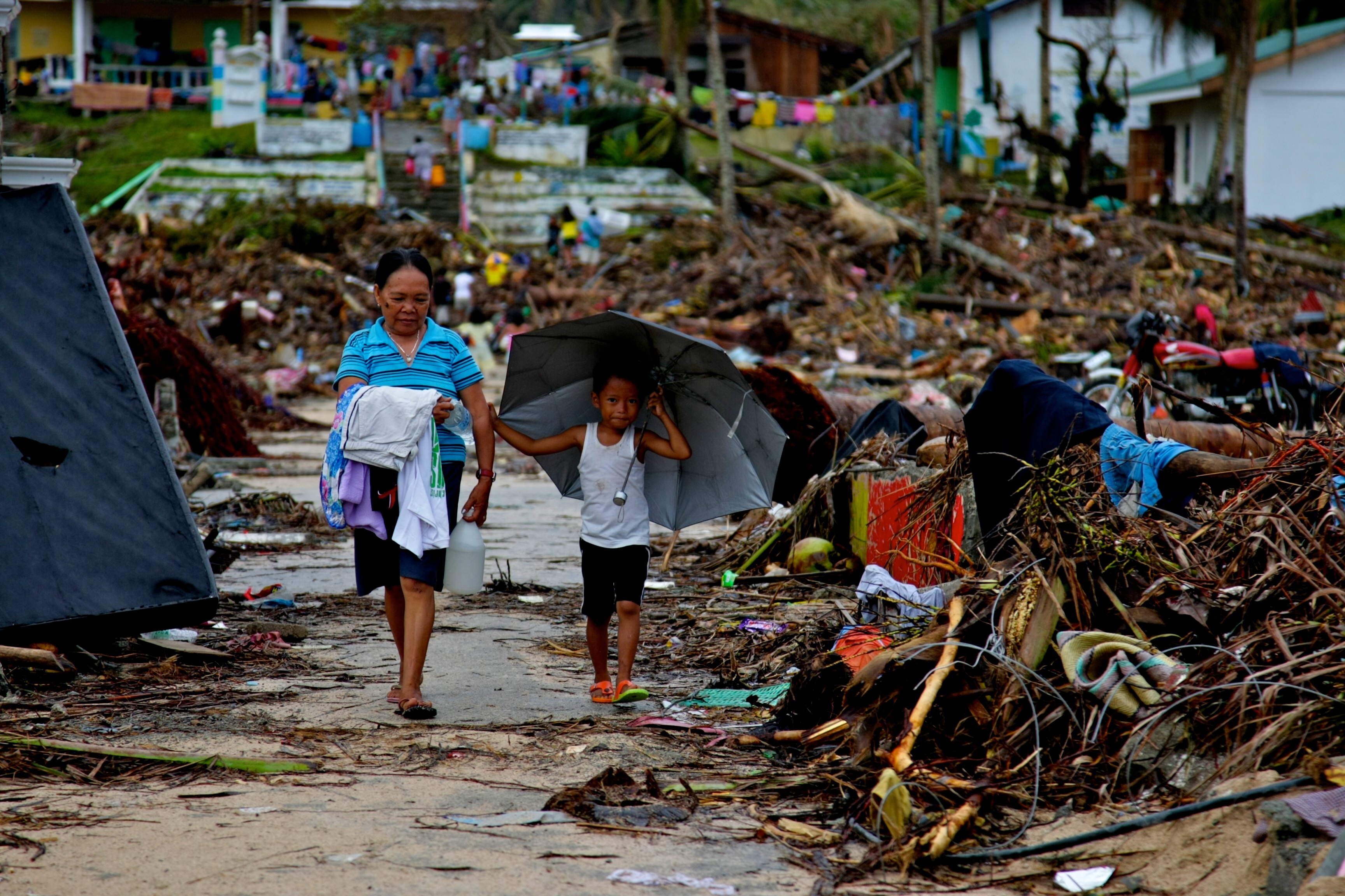 Residents walk past debris in East Samar, which Oxfam staff visited during an assessment in the aftermath of the Typhoon