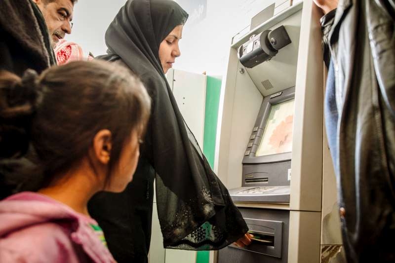 A Syrian refugee in Mafraq, Jordan takes cash from an ATM after using iris scan technology to identify herself.