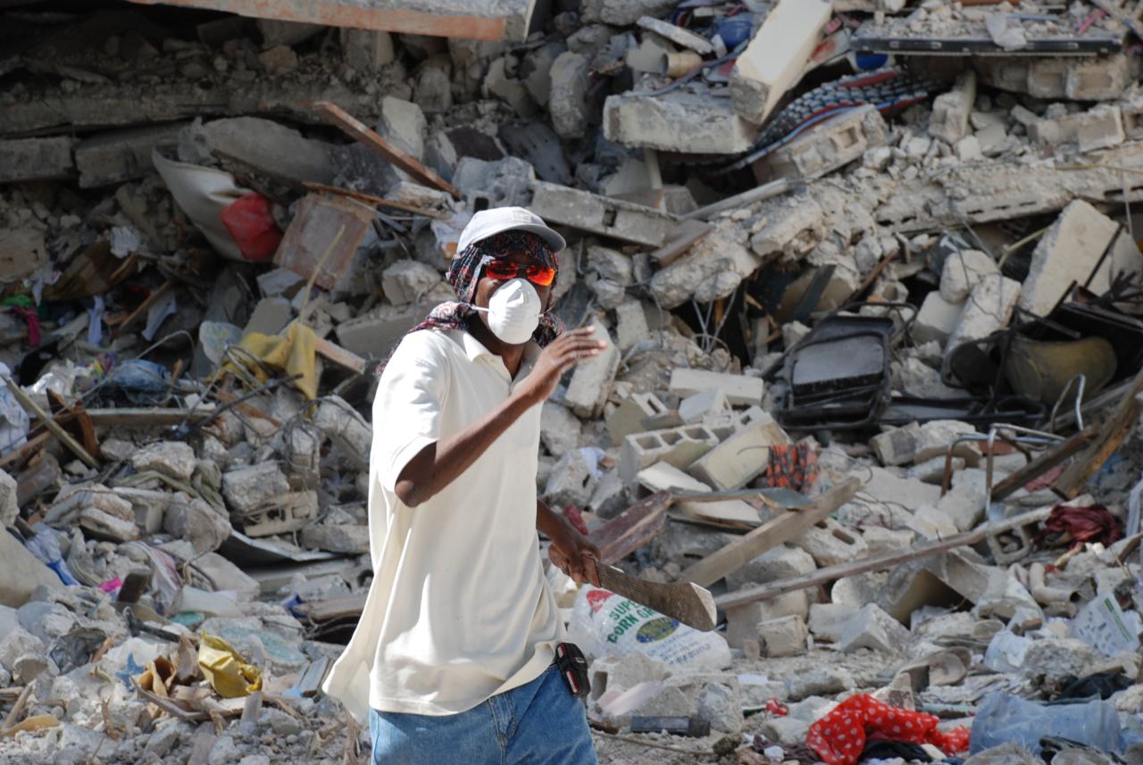A man in front of the pile of rubble that once was the Université Caraibes, Port-au-Prince, Haiti