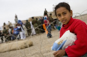 A young girl watches over the distribution of supplies in Kandahar, Afghanistan