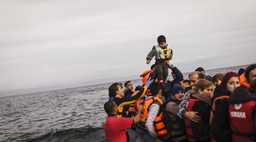 A man lifts his son in the air after reaching Lesvos, having crossed from the coast of Turkey to Greece.