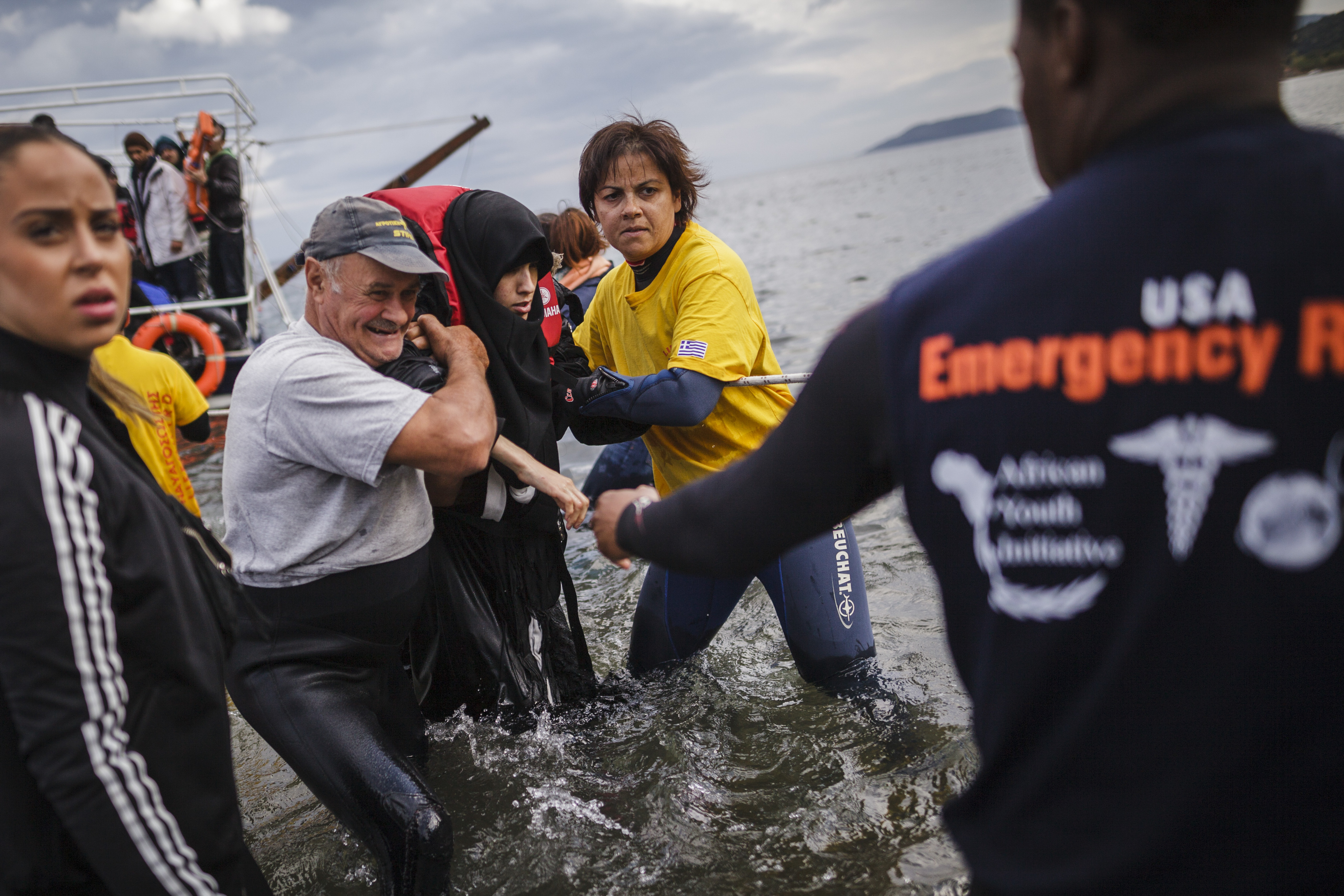 Volunteers help a Syrian refugee ashore on Lesvos, Greece.