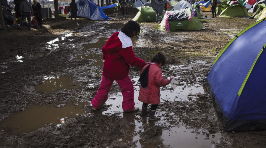 Two young girls walk through a makeshift camp near the village of Idomeni in Greece.