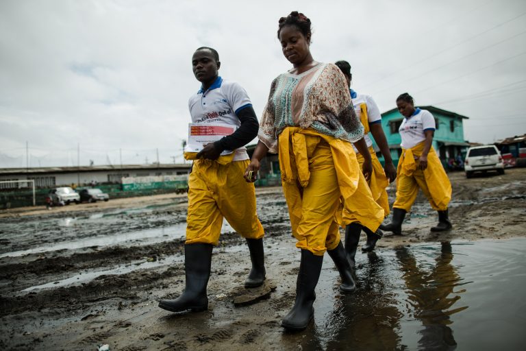 Community health volunteers with Ebola prevention kits walking through West Point in Monrovia, Liberia.