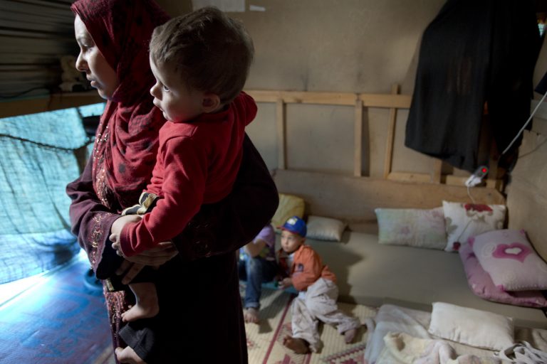 Elham, a Syrian refugee, holds her son Ahmad in their home in Kafar Kahel informal settlement in Koura District, Lebanon.