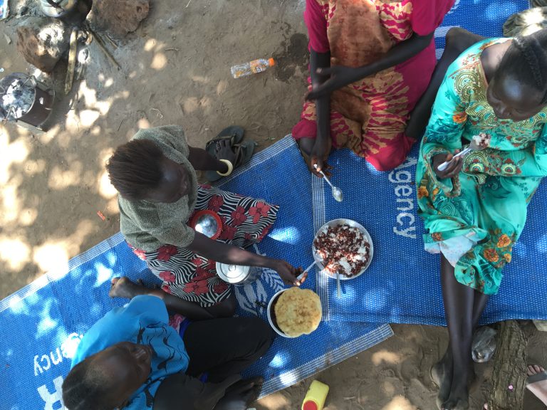 Women who run a small restaurant in Rhino Camp refugee settlement, Uganda. Here they share some leftover food.