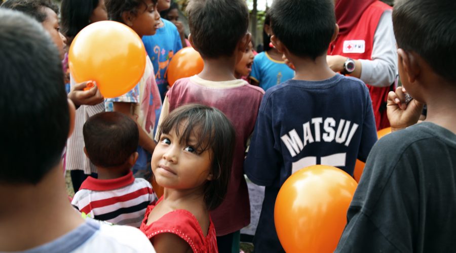 Children are entertained outside a PMI mobile medical clinic in a remote village in Donggala, Central Sulawesi, Indonesia.
