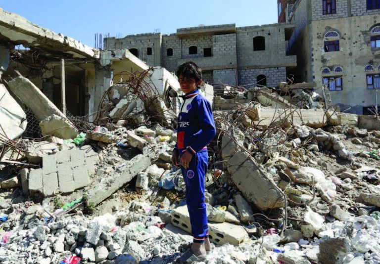 Sana’a. Ali, 13 years old, stands in the middle of destroyed buildings in his neighbourhood