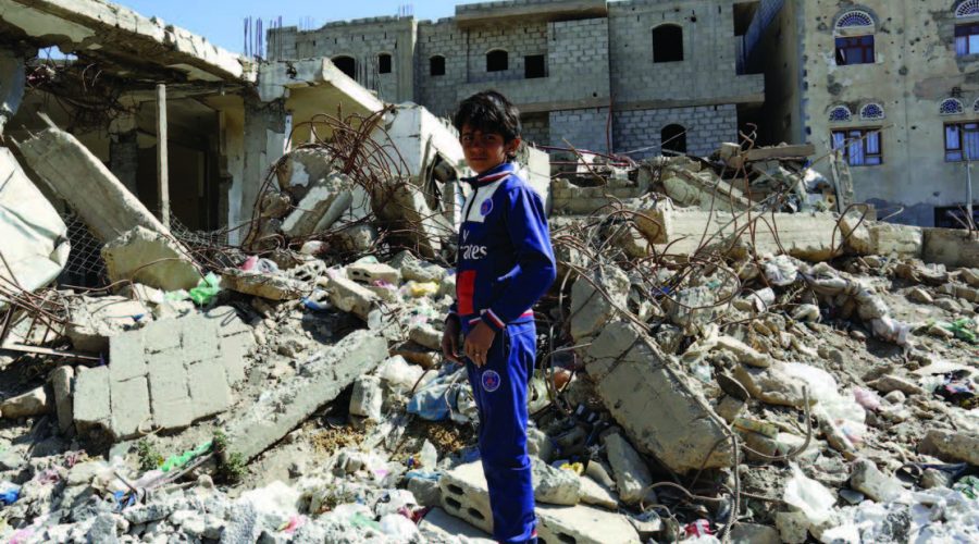 Sana’a. Ali, 13 years old, stands in the middle of destroyed buildings in his neighbourhood