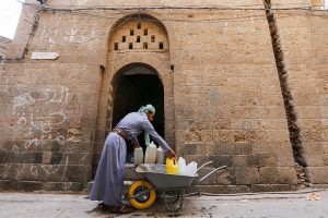 Yemen. Displaced in Sana’a’s Old City. 33 year old Mohammed Ali unloads jerry cans from his wheelbarrow in the Old City of Sana’a which will supply his family with safe water