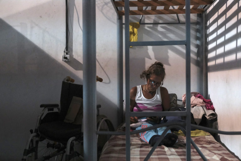 A woman with disabilities reads in her bed at the Coroado Shelter in Manaus.