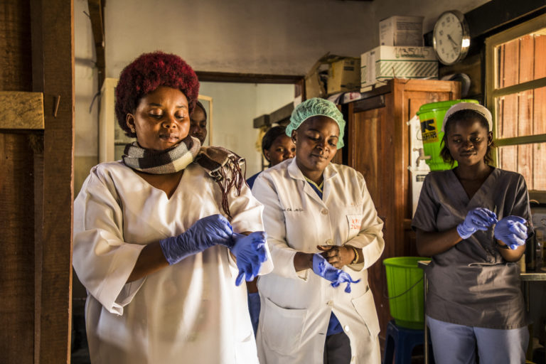 Health workers put their gloves on before checking patients at the hospital.