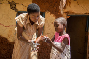 Octobre 2018, Nord-Kivu, République démocratique du Congo. Martine Kavucho, 30 ans, montre à sa fille Christine Botulu, 6 ans, les techniques de lavage des mains qu’elle a apprises au centre de santé dans le cadre de la réponse de Mercy Corps à Ebola